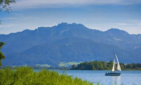 Segelboot auf dem Chiemsee in Bayern mit Berg Kampenwand